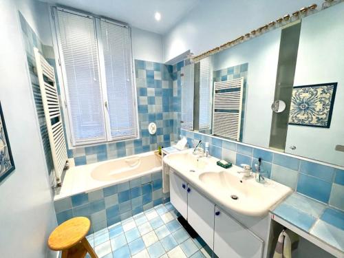 a blue tiled bathroom with a sink and a tub at Grand appartement Champ de Mars in Paris