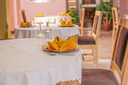 een tafel met een witte tafeldoek en een bord met gele servetten bij Hotel Wagon Wheel in Nakuru