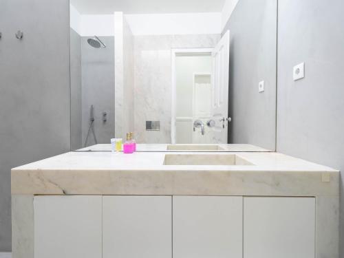 La salle de bains blanche est pourvue d'un lavabo et d'une douche. dans l'établissement Akicity Lisboa Iris, à Lisbonne
