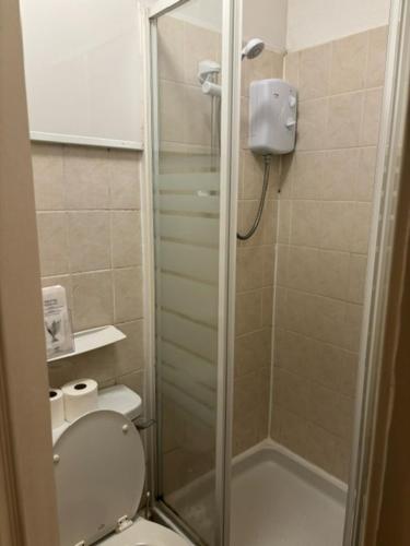 a bathroom with a toilet with a glass shower stall at Argyll guest house in Blackpool