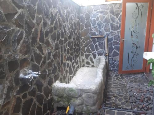 y baño con ducha de piedra con banco. en Bali Homestay en Tejakula