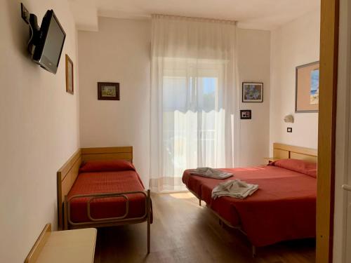 リミニにあるHotel Tre Grazieのベッドルーム1室(ベッド2台、窓付)