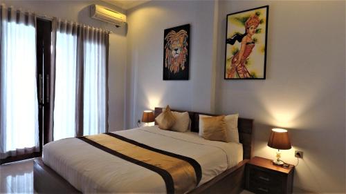 ペニダ島にあるPradana Beach Inn Luxuryの大きなベッド付きのベッドルーム1室、壁に絵画が飾られています。