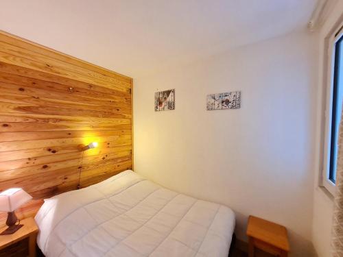 une chambre avec un lit blanc et un mur en bois dans l'établissement Meije 5 - C3 - Appart 4 pers proche pistes, à Les Deux Alpes