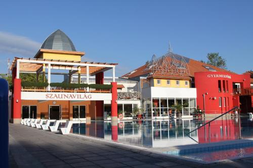 un groupe de bâtiments avec une piscine devant lui dans l'établissement Farkas Villa, à Mórahalom