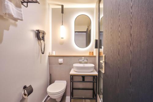 a bathroom with a sink and a toilet and a mirror at Campanile Paris Ouest - Pont de Suresnes in Suresnes