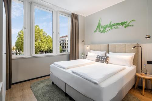 Un dormitorio con una gran cama blanca y una ventana en KOOS Hotel&Apartments - City Aparthotel, en Múnich