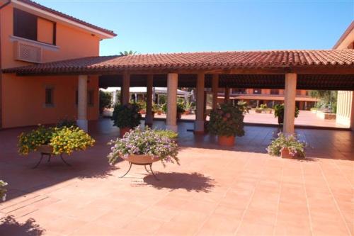 a patio with two benches and flowers in front of a building at Residence Porto Coda Cavallo in San Teodoro