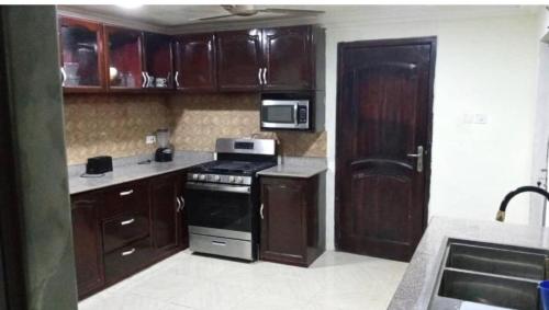 una cocina con armarios de madera y estufa negra en Villa at Grace, en Cape Coast