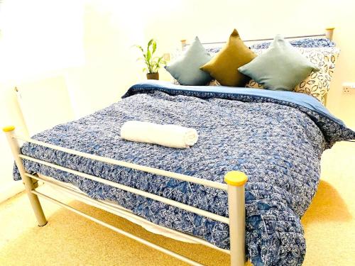 a bed with a blue comforter and pillows at North Greenwhich Homestay in London