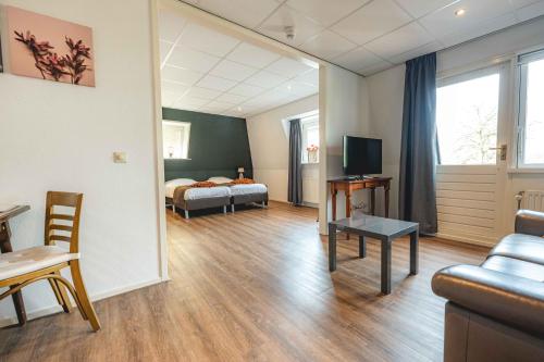 a room with a bed and a couch and a tv at De Klomp Charme Hotel & Restaurant in Vilsteren