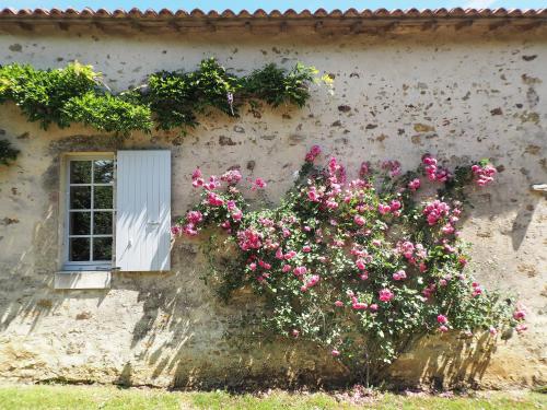 a building with pink flowers and a window at Logis La Tour - Gîte Orangerie in Saint-Laurent-de-la-Salle