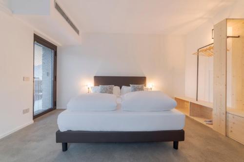 a white bedroom with a large bed and a window at Agriturismo B&B Caffè e Vino in Sondrio