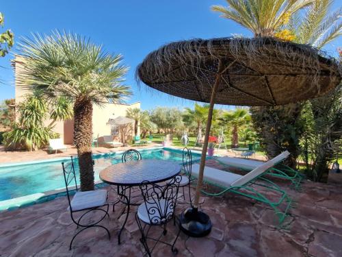 un tavolo e sedie con ombrellone accanto a una piscina di Manzal Lahbab (Pavillons, Bungalows, Piscine et Jardins) a Marrakech