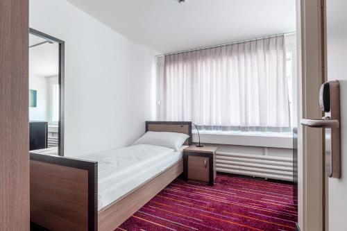 1 dormitorio con cama con espejo y ventana en Union Light - Self Check-In Hotel en Luzern