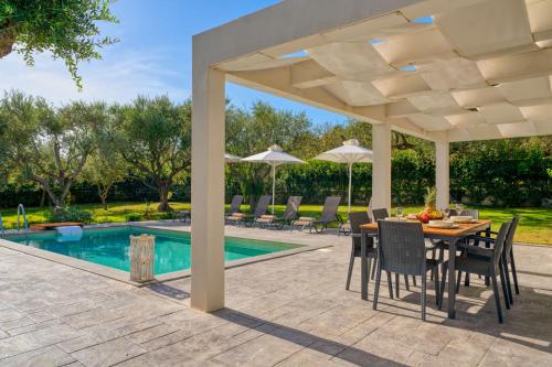 a patio with a table and chairs and a pool at Valeria Private Villa in Plános