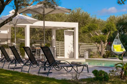 a group of chairs and an umbrella next to a pool at Valeria Private Villa in Plános