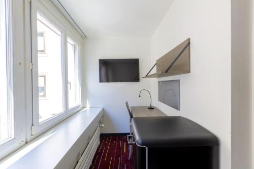 Dieses weiße Zimmer verfügt über ein Waschbecken, einen TV und Fenster. in der Unterkunft Union Light - Self Check-In Hotel in Luzern
