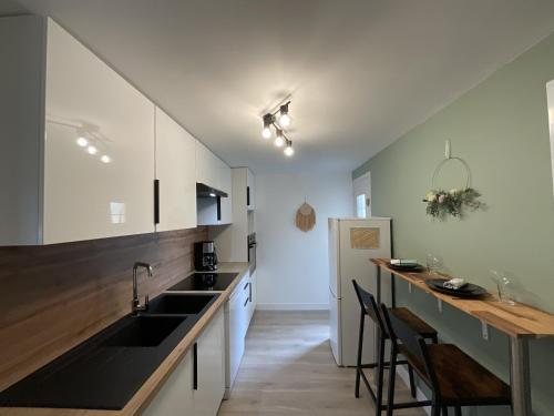 une cuisine avec des armoires blanches et des comptoirs noirs dans l'établissement Le Bener - Proche Centre - 6 pers, à Yvré-lʼÉvêque