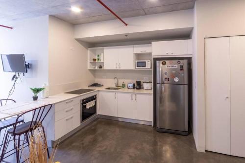 a kitchen with white cabinets and a stainless steel refrigerator at 2512 URBN Escalante Hermoso Loft SIN PARQUEO in San José
