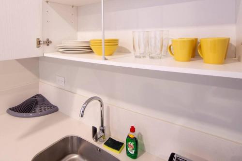 a kitchen with a sink and a shelf with dishes at 2512 URBN Escalante Hermoso Loft SIN PARQUEO in San José