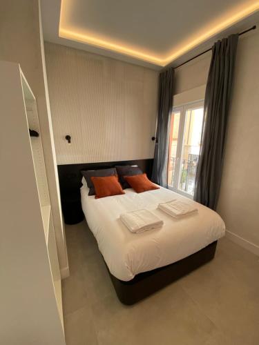 1 dormitorio con 1 cama con sábanas blancas y almohadas de color naranja en Apartamentos "El collado Suites" Soria Centro, en Soria