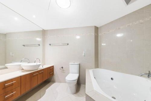a bathroom with a tub and a toilet and a sink at Lux Sub-Penthouse with Casino views in Brisbane
