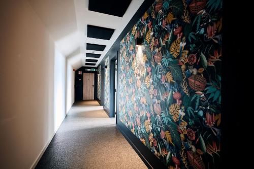 a hallway with a wall with a floral wallpaper at Le Mont Rigi in Waimes