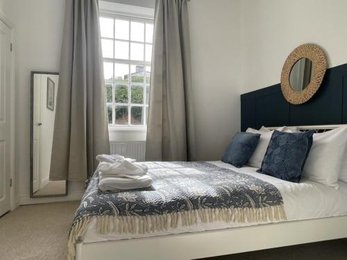 ein Schlafzimmer mit einem Bett mit blauen Kissen und einem Spiegel in der Unterkunft Apartment 2 St Georges in Cheltenham