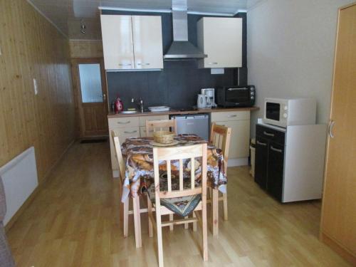 een keuken met een tafel en stoelen en een koelkast bij Au P'tit Grillon in Salins-les-Bains