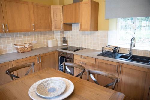 Longwitton的住宿－Gardeners Cottage，厨房配有木桌和水槽。