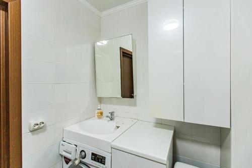 a white bathroom with a sink and a mirror at Maulenova 32.36 kv41 in Almaty