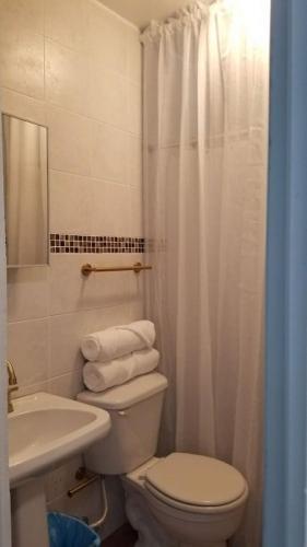 a white bathroom with a toilet and a sink at Beachfront Luxury Apartment in Aguada