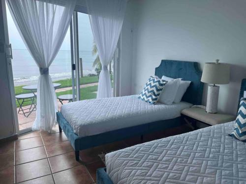 a bedroom with two beds and a view of the ocean at Beachfront Luxury Apartment in Aguada