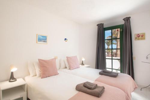 two beds in a room with a window at CASA PAZ - COZY 2 BEDROOM APARTMENT CLOSE TO DORADA BEACH in Playa Blanca