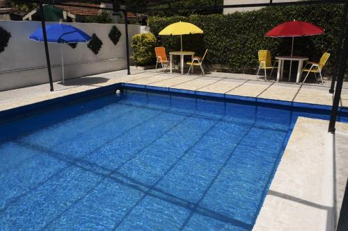 una piscina con 2 sombrillas y 2 mesas y sillas en Hotel Bellavista en Villa Carlos Paz