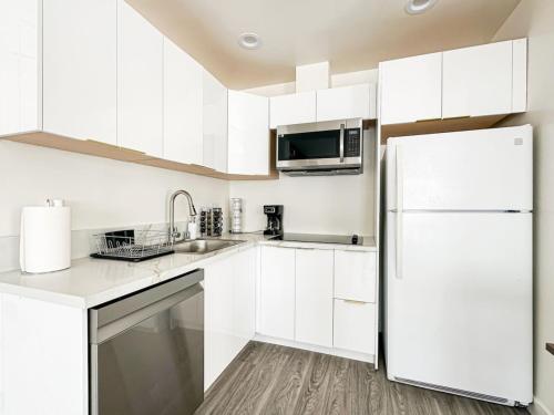 a white kitchen with white cabinets and a refrigerator at Cozy Guesthouse in LA (WO2 - BUR) in Burbank