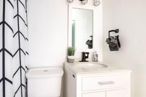 a bathroom with a toilet and a sink and a mirror at Encanto house with king bed in Isabela