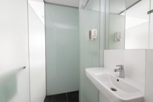 a white bathroom with a sink and a mirror at easyHotel Rotterdam City Centre in Rotterdam