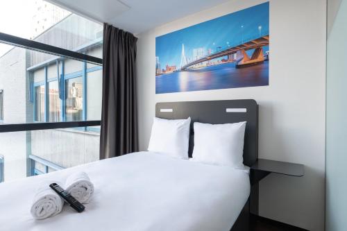 een slaapkamer met een wit bed en een groot raam bij easyHotel Rotterdam City Centre in Rotterdam