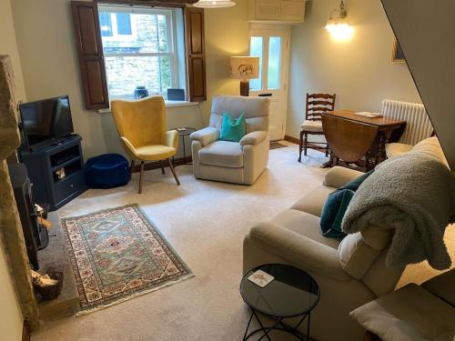 a living room with a couch and chairs and a tv at Peaceful cottage Peak District, nr Bakewell in Buxton