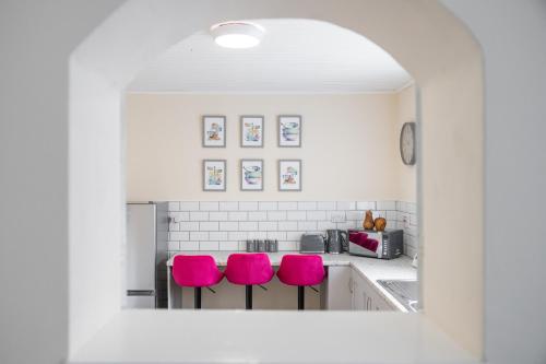 a kitchen with pink chairs in a white kitchen at Varden House in Derry Londonderry
