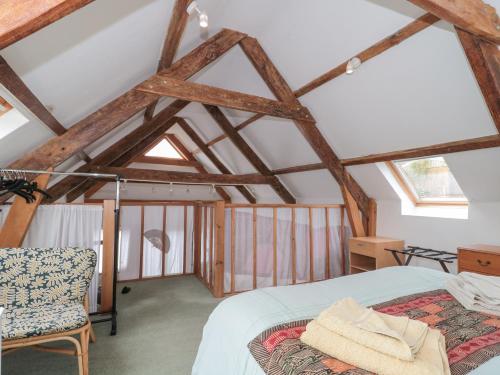 1 dormitorio en el ático con 1 cama y 1 silla en Higher Putham Barn, en Wheddon Cross