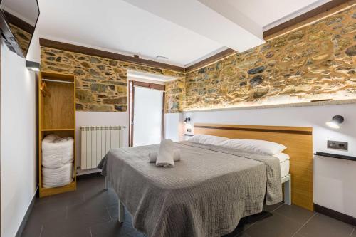 a bedroom with a bed and a stone wall at Albergue O Candil in Melide