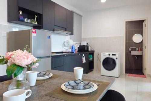 eine Küche mit einem Tisch mit Tellern und Blumen darauf in der Unterkunft NEW Elegant & Cozy Greenfield Home near Sunway 2-6pax in Petaling Jaya