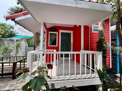 une maison rouge et blanche avec une véranda blanche dans l'établissement MrT Riverside Sampran มิสเตอร์ที โฮมสเตย์-ทองกวาว, à Sam Phran