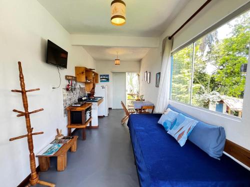 ein Wohnzimmer mit einem blauen Sofa und einem großen Fenster in der Unterkunft Vila Boa Vista Itacaré in Itacaré