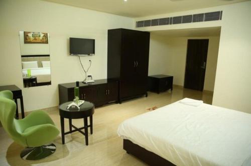 a bedroom with a bed and a chair and a television at SREE VEDA INN in Guntūr