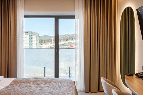 a hotel room with a bed and a large window at Tavel Hotel & SPA in Bukovel