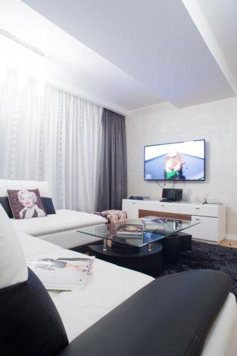 a living room with white furniture and a flat screen tv at The Queen Luxury Apartments - Villa Marilyn in Luxembourg